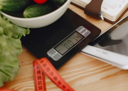 A bowl of fresh vegetables on a kitchen scale with measurement tools, depicting a healthy lifestyle.